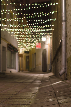 Blurred image of narrow city street decorated with illuminated festoonの写真素材