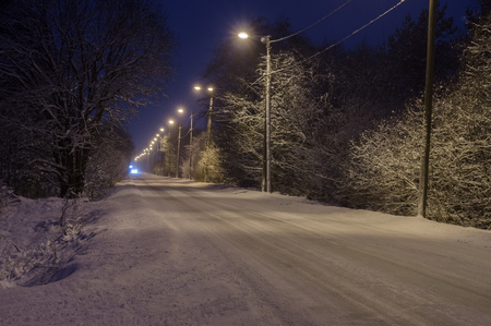 Snow-covered rural road by nightの写真素材