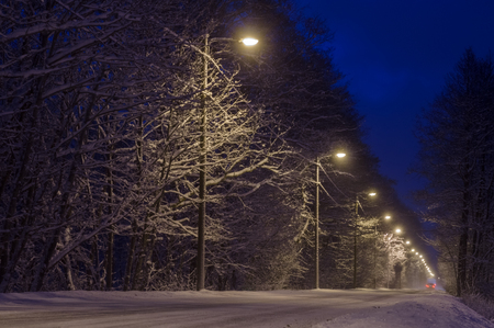 Countryside road covered with snow by nightの写真素材