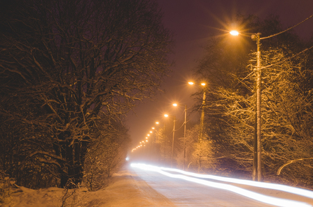 Front lights of car on snowy road by winter night, long exposure imageの写真素材