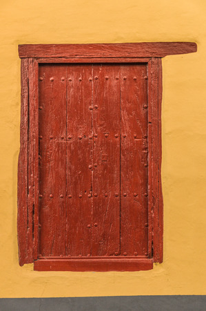 Yellow plaster wall with red wooden doorの写真素材