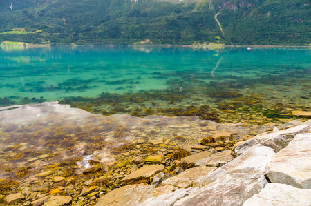 Norwegian stony fjord coast and colorful transparent waterの写真素材