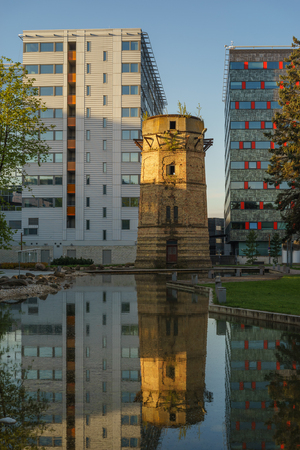 Tallinn, Estonia - May 21, 2016: Old abandoned water-tower and modern business buildings side-by-side with reflection in pond. Hi-tech Ulemiste city area.のeditorial素材