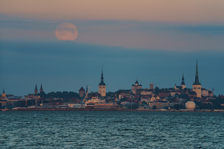 Full moon over Old town of Tallinn city, Estonia. Moonset before sunriseの写真素材