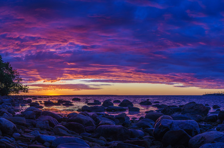 Panorama of stony coast of Baltic sea by vivid sunset with fiery cloudscapeの写真素材