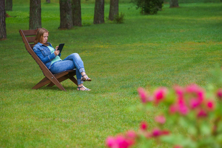 Serious young woman working on a tablet PC in summertime garden.の写真素材