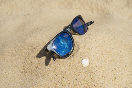 Reflecting sunglasses on sandy beach with shell. Selective focusの写真素材