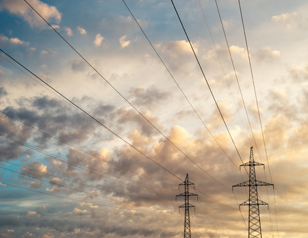 High voltage line against scenic cloudscape, colorful sunrise skyの写真素材