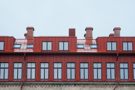 Top part of modern house with many windows, chimneys, rain-pipe and atticの写真素材