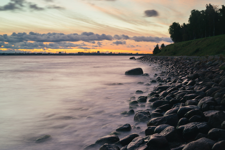 Sunrise long exposure of stony seacoast with Tallinn city skyline on backgroundの写真素材
