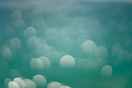 Big oval bokeh lights on turquoise lake water, abstract backgroundの写真素材