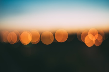 Abstract background of bright orange bokeh lights with smooth defocused effect, blurred skyline after sunsetの写真素材