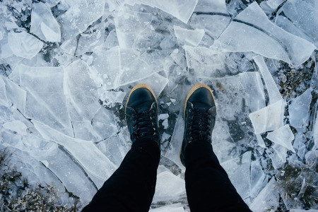 Male legs in leather boots standing on cracked ice, top viewの写真素材