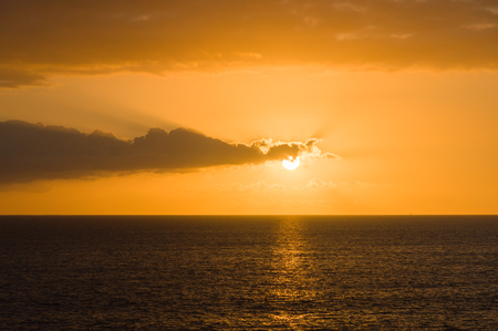 Wonderful sunset at over, partly hidden sun by cloudsの写真素材