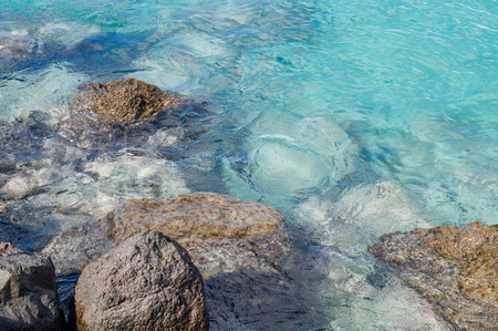Stones and transparent turquoise water, ripple on surfaceの写真素材