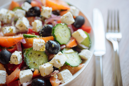 Greek salad with feta cheese, black olives, tomato, cucumber and onion. Selective focus, flatware on backgroundの写真素材
