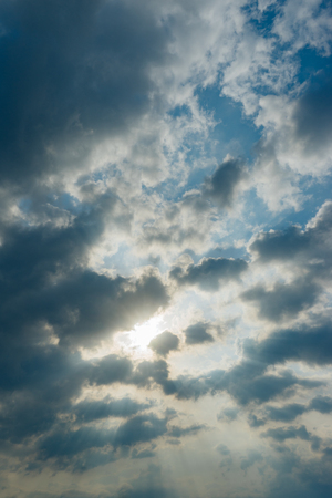 Sunbeams striking through the clouds on blue sky, nature backgroundの写真素材