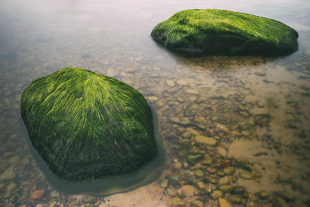 Two green stones in water of Baltic sea. Long exposure imageの写真素材