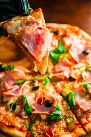 Taking a piece of freshly baked homemade pizza with stretching cheese. 4K close upの写真素材