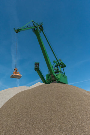 Green green grab crane fills sand from one hill to the otherのeditorial素材