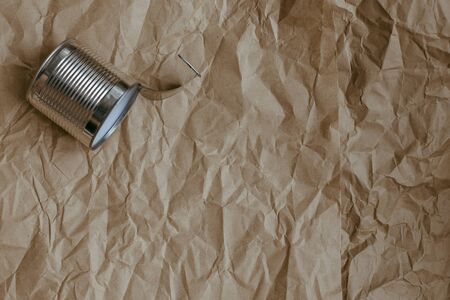 Used iron tin can on a plain crumpled brown kraft paper background. Environmental pollution concept,...
