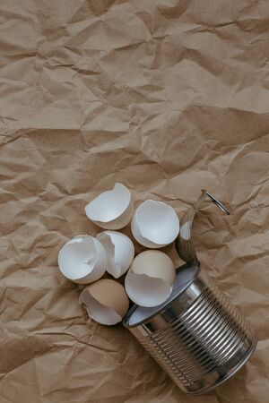 Eggshell in tin top view. Creative still life photo of an Eggshell in a tin can on brown background.