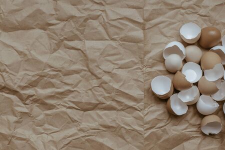 Texture of broken empty eggshell on a crumpled brown kraft paper background. View from above. Copyspace.の写真素材