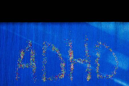 ADHD written with pastry sprinkles on a blue background. ADHD is Attention deficit hyperactivity disorder. Copyspace.の写真素材