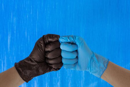 handshake in black and blue gloves isolated on blue background. Place for text. Copy space.の写真素材
