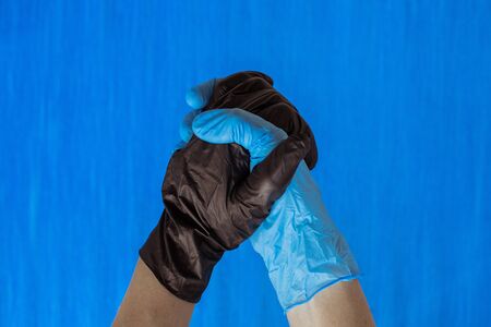 handshake in black and blue gloves isolated on blue background. Place for text. Copy space.