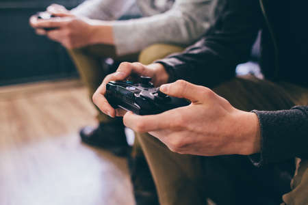 A young man holding a black game controller for the Microsoft Xbox, a video game console.のeditorial素材