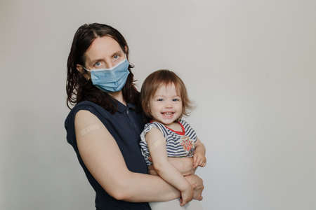 mother and daughter, a child after vaccination. A woman in a medical mask. Happy joyful childの写真素材