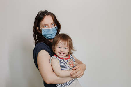 mother and daughter, a child after vaccination. A woman in a medical mask. Happy joyful childの写真素材