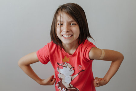 Portrait of a young girl shows arm with patch, after having the vaccine against Coronavirus Covid-19...