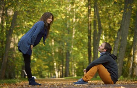 Side portrait of young pregnant woman standing in dress and sitting happy man, smiling each other. 9...