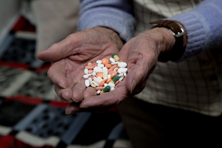Old woman is holding medications in her handsの写真素材