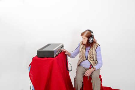 Elderly lady listening attentively radio with headphones.の写真素材