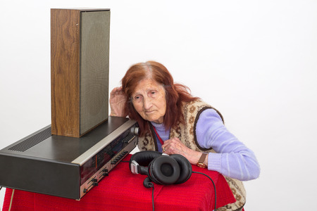 Elderly woman with the hand on her ear, trying to hear radioの写真素材