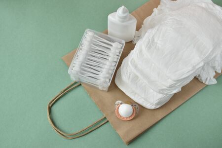 Child care items on a paper bag on a green background look from the top.の写真素材
