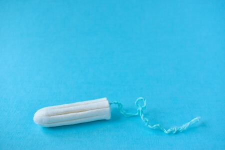 A women's tampon, isolated on a blue background.