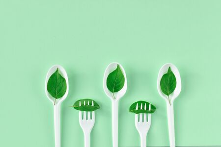 Plastic cutlery on a green background with place for text. Minimalism. Plastic cutlery Ecology....