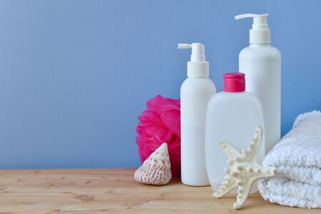 Personal hygiene products. Body care cosmetics. Plastic bottles, towel and cockleshells on a light...