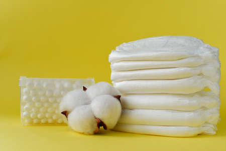 Baby diapers with cotton buds and dried cotton closeup on yellow with copy space.の写真素材