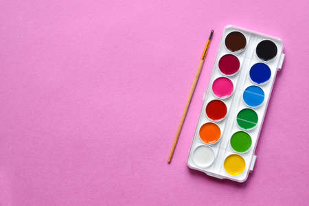 Watercolor paints with a brush on a pink background. Creation. School.の写真素材