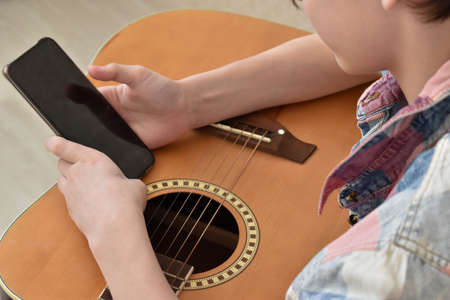 A boy learns to play the guitar through online lessons