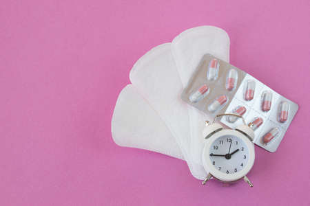 Daily womens pads and capsules in a blister on a pink background. The concept of pain pills from PMS.の写真素材