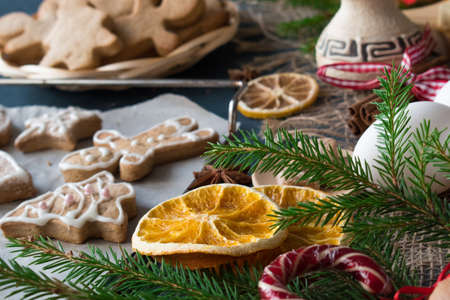 Close-up of a spruce branch and orange slices on the background of glazed cookies.