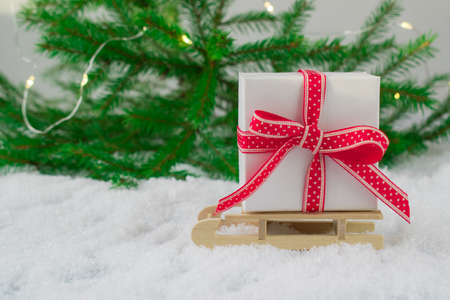 New years frame. Christmas card. Banner. Gift box on a wooden sled on the snow on the background of...