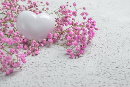 Background with small pink flowers and a white heart. There is room for text.
