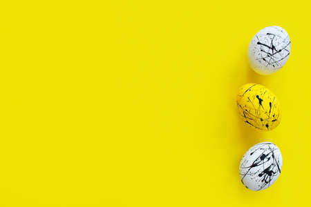 Three Easter eggs on a yellow background. Happy Easter. Minimalism. Background with a copy of the...